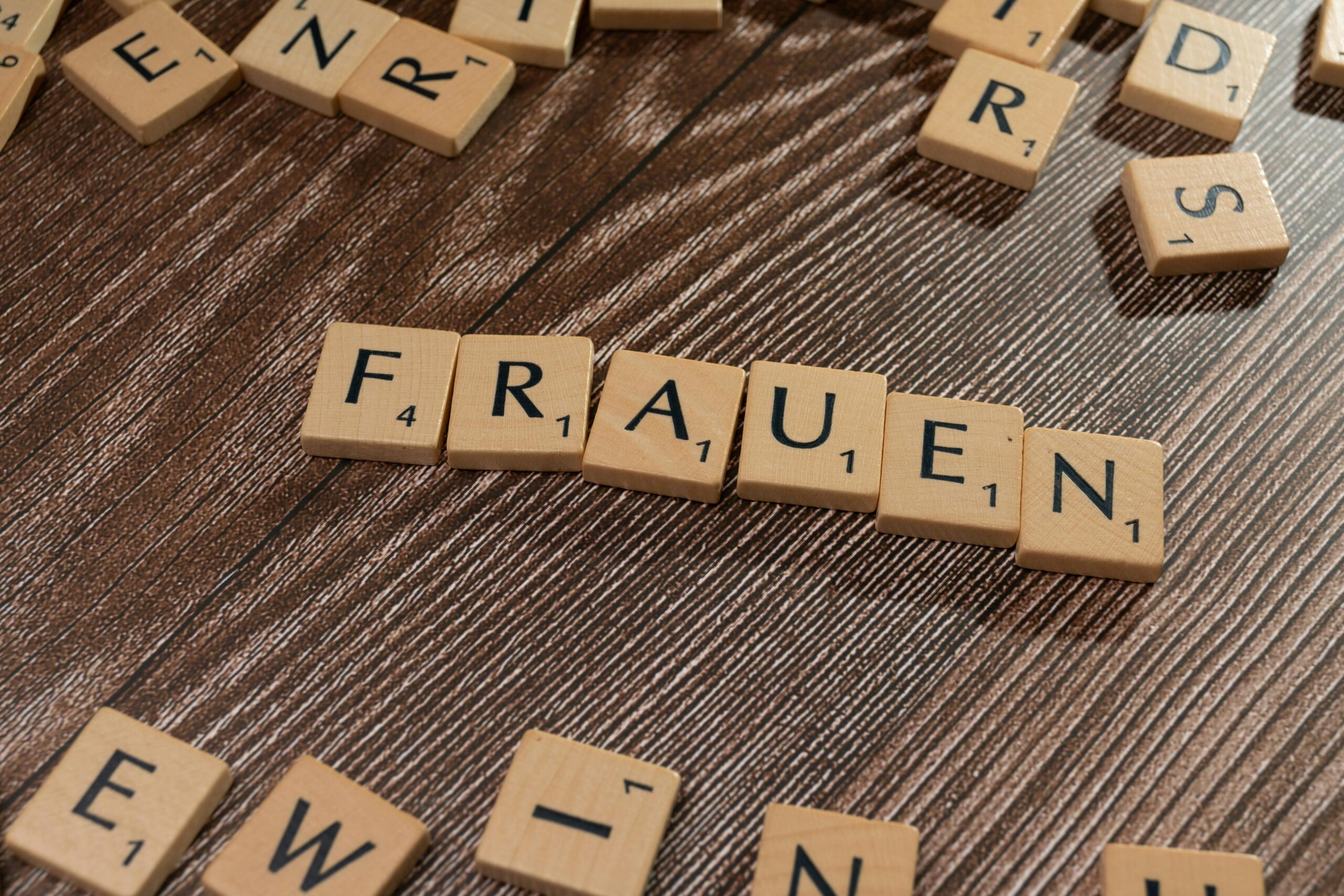 Close-up of wooden tiles spelling 'Frauen' on a wooden surface, high angle.